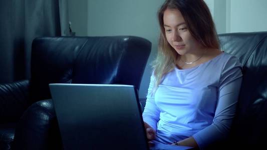 可爱的亚洲女人在晚上使用笔记本电脑