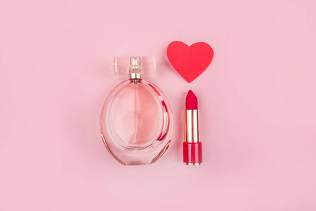 情人节平板与美容产品瓶香水，红色口红和纸心粉色背景。