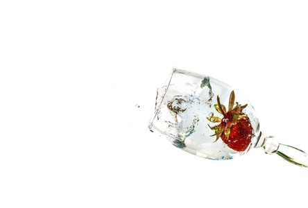 草莓倒在一杯白色背景的水中