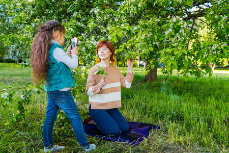 母亲和女儿在春天公园的苹果树开花附近玩的肖像。