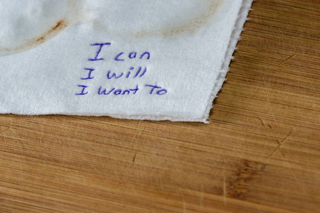 手写的纸条上的咖啡染色餐巾纸与一个授权的信息，我可以，我会想。