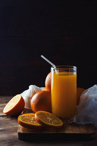 一杯橙汁，一片橘子切片，放在木板上，背景很黑。 光明和阴影的美丽游戏。