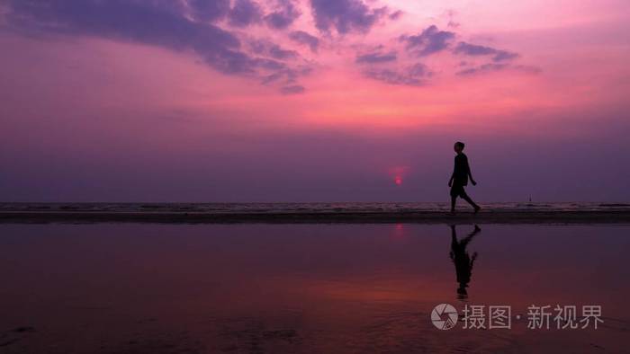 孤独的亚洲年轻人在日落时平静地沿着荒芜的海滩散步.海景
