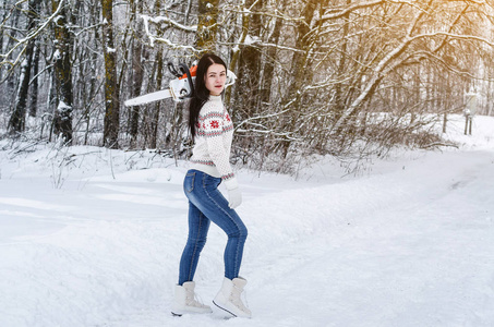 可爱开朗的女孩带着电锯穿过树林里的雪。砍伐森林伐木柴火伐木设备