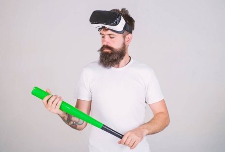 时尚的胡子测试虚拟现实游戏设备时髦。有胡子的人在 Vr 耳机持有棒球蝙蝠孤立的灰色背景。游戏玩家与书胡子玩模拟运动游戏