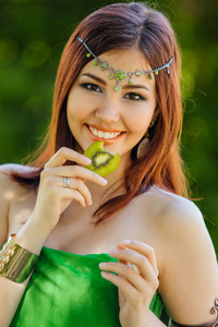 一位穿着绿色连衣裙戴德玛头上拿着猕猴桃片的美丽年轻亚洲女人的肖像。