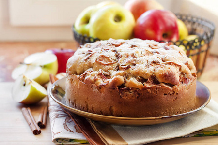 自制的苹果派，盘子里有肉桂，背景是绿苹果和红苹果