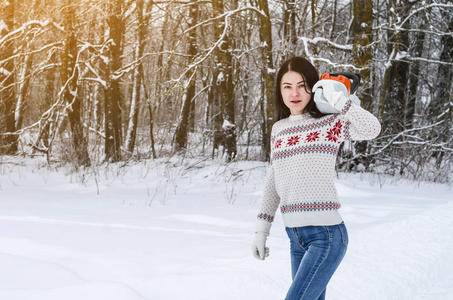 穿着白色温暖毛衣的可爱开朗的女孩带着电锯在树林里下雪。 砍伐森林砍柴伐木设备