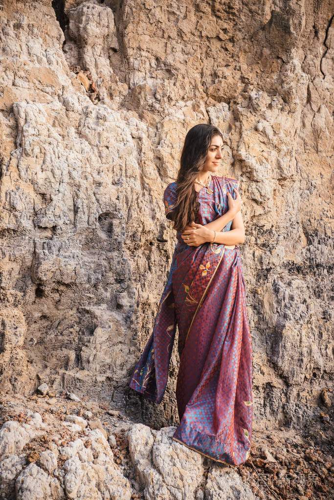 印度妇女传统服装时尚拍摄. 站在海滩附近的岩石上的一位美丽的女士