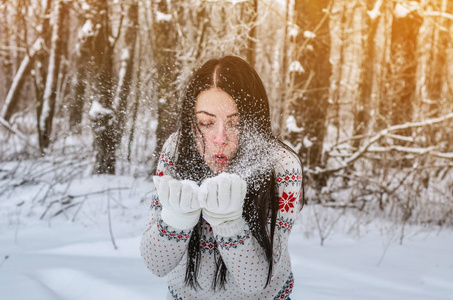 一个在白雪覆盖的森林里的女人把雪扔在背景树上。 冬季娱乐休闲娱乐