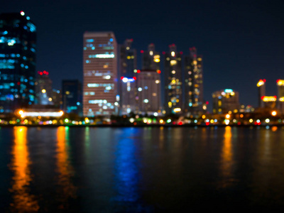 模糊的照明摩天大楼在曼谷的河边在晚上。 金融区背景。