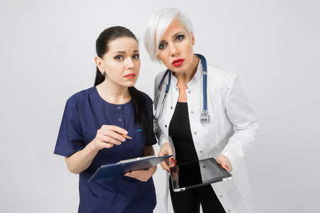 两名女医生用片剂和床单, 双手分析, 在白色背景上隔离