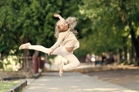 快乐的女孩在夏日公园里跳得很高。小孩子微笑着飞发在运动感觉自由。时尚的孩子在户外玩得开心。自由和能量。自由感。儿童活动与活动游戏