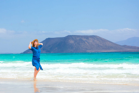 穿着蓝色裙子的快乐女旅行者在热带海滩度假