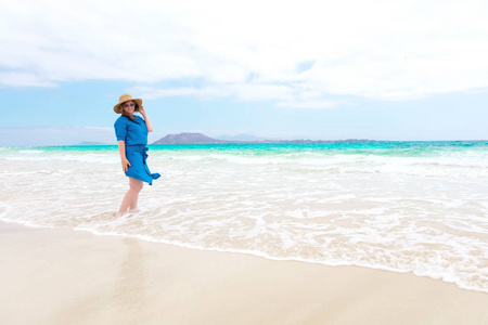 穿着蓝色裙子的快乐女旅行者在热带海滩度假