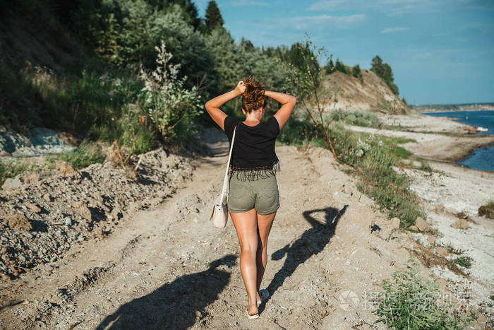 美丽的女性与完美的晒黑腿在海岸线上的海岸线在农村的背面