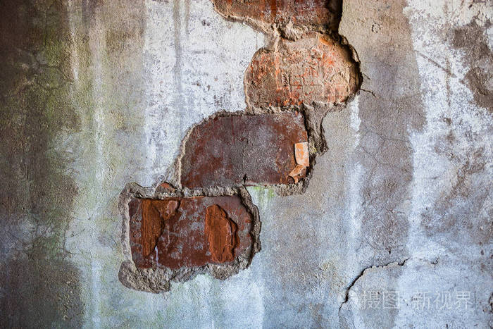 在旧墙的裂开石膏中可见的砖块。