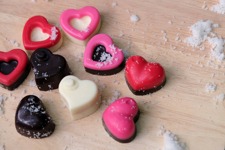 五颜六色的牛奶巧克力心放在木盘和雪地上，是情人节的概念。