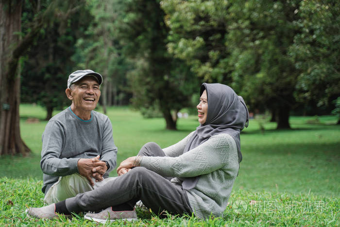 成熟的老人和女人坐在公园里的草地上