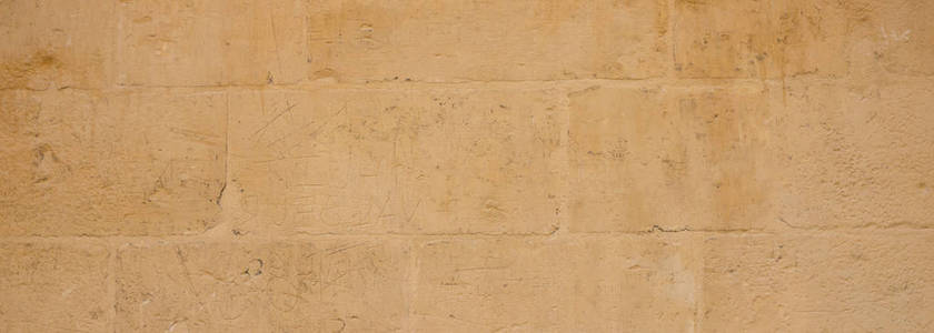 天然石材背景纹理黄色米色。 马耳他旗帜传统石灰石墙立面背景