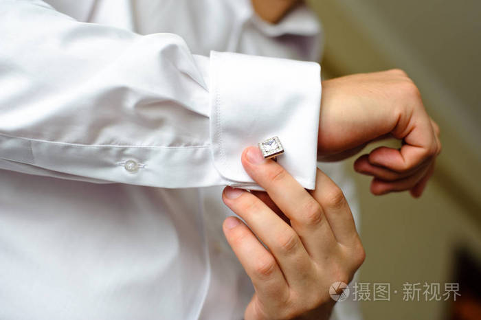 新郎把袖扣系在衬衫的袖口上 新郎在婚礼当天的早晨聚会 商人把袖扣系在衬衫的袖口上 照片 正版商用图片184jge 摄图新视界