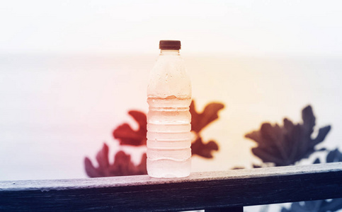 一瓶干净的饮用水，放在一个带有红灯的自然背景上，这是纯洁和健康的概念
