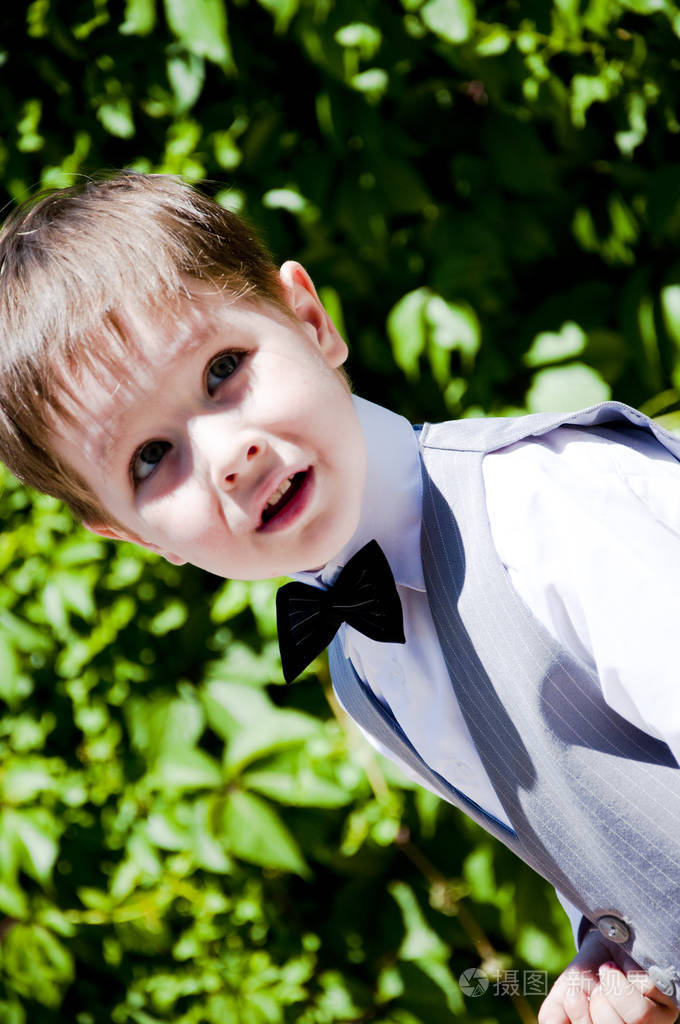 可爱的小男孩或绅士的孩子微笑着穿着正式的灰色西装背心白色衬衫和