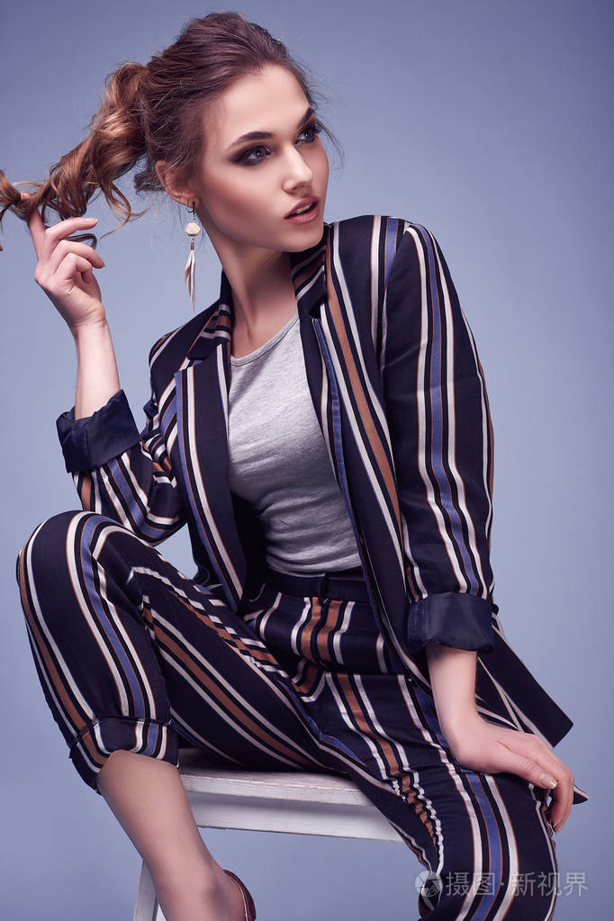 性感的肖像,优雅的魅力女人,时尚西装,摆在彩色蓝色背景在工作室.