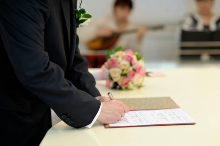 新郎把他的签名放在结婚文件里。