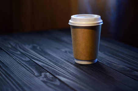 桌子上有一杯咖啡。 纸杯木桌塑料帽咖啡期待。 咖啡在咖啡厅带走。 模拟背景的概念