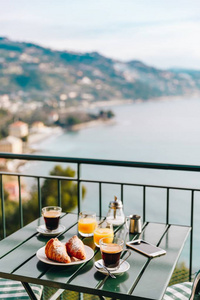 意大利海景阳台上提供美味的早餐，包括咖啡糕点和橙汁。