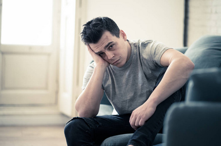 男性焦虑不高兴沮丧的白种人男性坐在客厅的沙发上哭泣,感到绝望,孤独