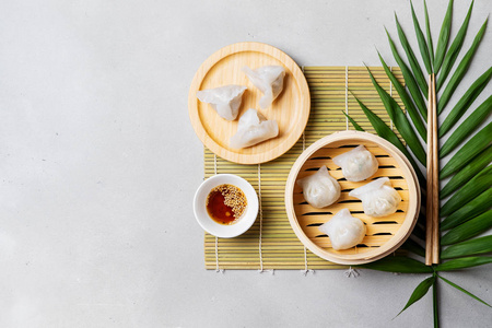 中国传统蒸饺，竹蒸蒸笼，在浅色背景上加酱和筷子