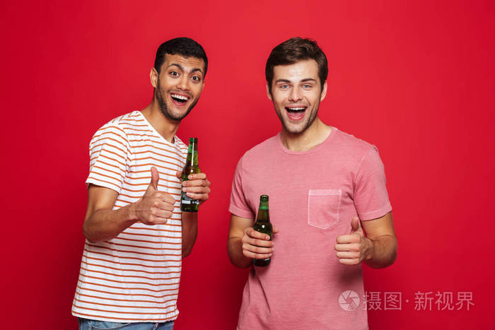 两个快乐的年轻人站在红色背景下，从瓶子里喝苏打水