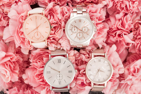 放在盛开的粉红色花朵上的手表的俯视图