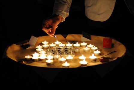 人们点燃站在托盘上的小蜡烛。 在黑暗中点燃蜡烛。