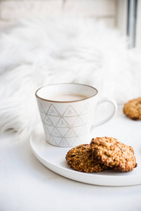 舒适的周末早餐，铺毛毯白色咖啡杯和陶瓷托盘上的饼干温暖的灯光家庭内部装饰特写