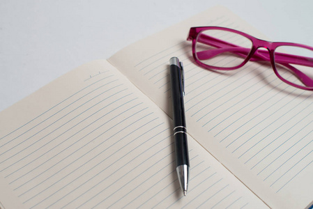 笔记本上有黑色钢笔彩色记事本书桌上的眼镜笔和一杯咖啡电脑键盘和彩色纸条