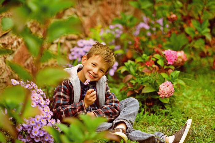 快乐的男孩享受春天的花朵.小男孩在春天的花园里放松一下.