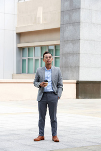 成功的时尚越南企业家站在户外，手里拿着一杯咖啡