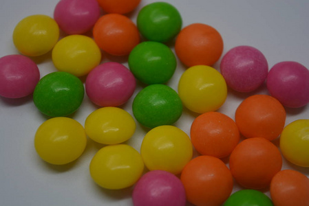 明亮的甜和美味的糖果，黄色，粉红色，橙色，绿色的窗帘在白色的背景上。
