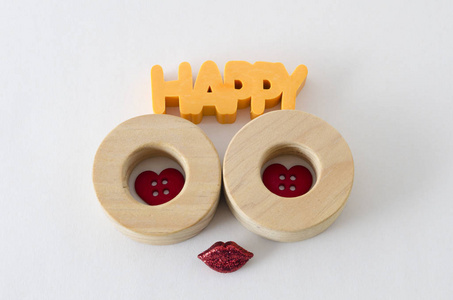 快乐的词在黄色和两个木制的圆圈，小红色的纽扣心和闪亮的红色嘴唇在白色的背景下。