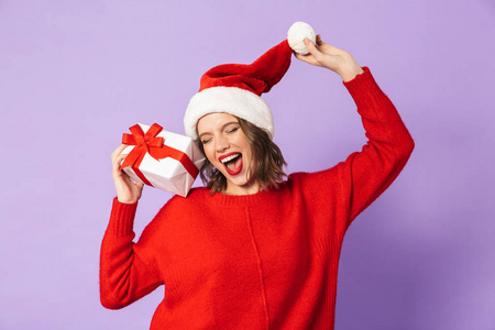 穿着红色圣诞帽的年轻女子，与紫罗兰背景隔绝，手持礼品盒
