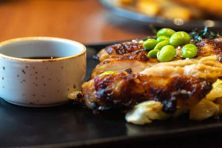 用黑色盘子上的一杯酱汁把鸡肉牛排合上。 在餐厅里用白甘蓝胡萝卜和蘑菇制作的鸡肉牛排上的青豆和日本海藻