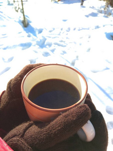 在白色的雪背景上手拿着一杯咖啡