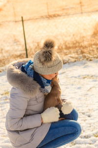 年轻的女人在外面雪地里玩得很开心。 雌性在寒冷的冬天和她的小纯种狗小狗玩耍。