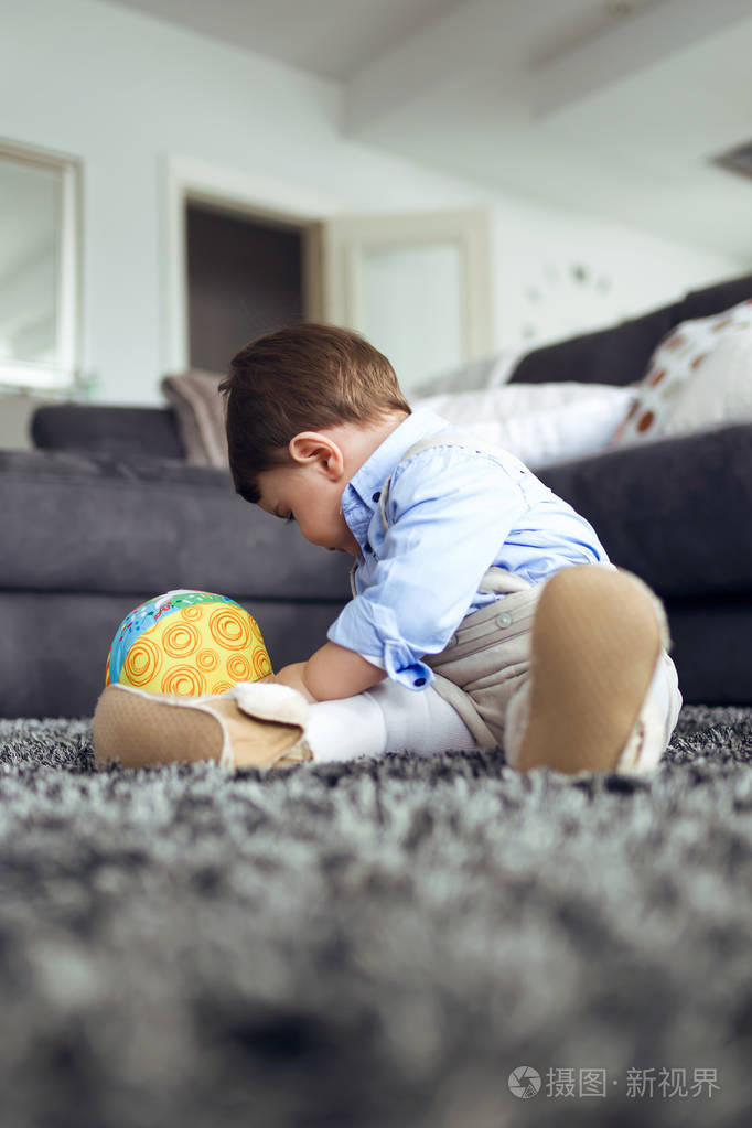 美丽的婴儿在家客厅的地板上玩球的镜头.