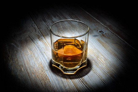 黑色背景的老式木桌上的一杯威士忌。