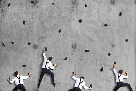 商业理念一群员工爬上混凝土墙。
