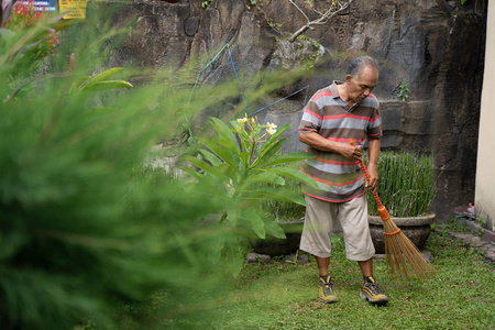 高级亚洲男性扫他的花园
